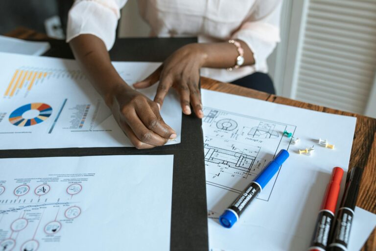 Photo by RDNE Stock project - BizRanger Hub An adult working on business charts and design blueprints in an office setting.