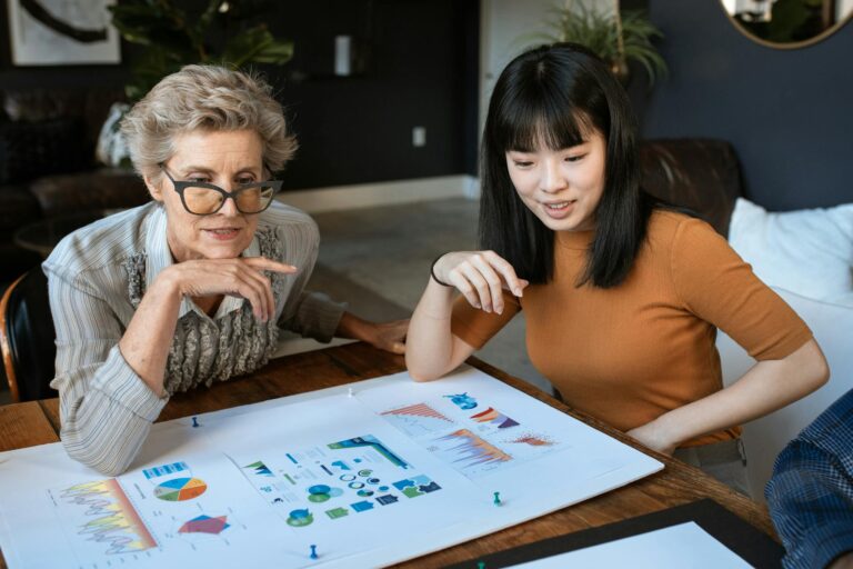 Photo by RDNE Stock project - BizRanger Hub Two women discussing charts at a modern office desk, showcasing business collaboration.